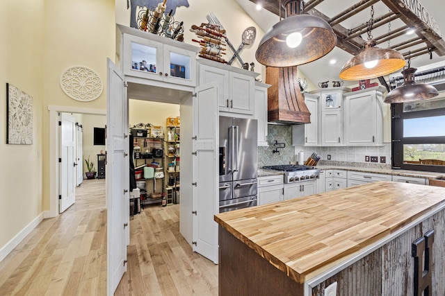kitchen featuring light wood-type flooring, white cabinets, custom exhaust hood, appliances with stainless steel finishes, and wooden counters