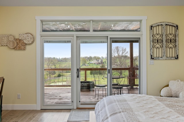 bedroom featuring access to outside, wood finished floors, and baseboards