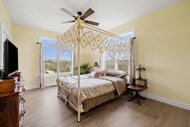 bedroom featuring baseboards, light wood finished floors, and a ceiling fan