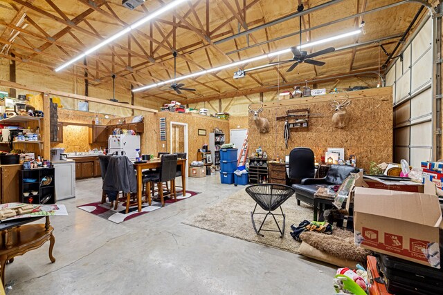 garage featuring a ceiling fan, freestanding refrigerator, and a workshop area