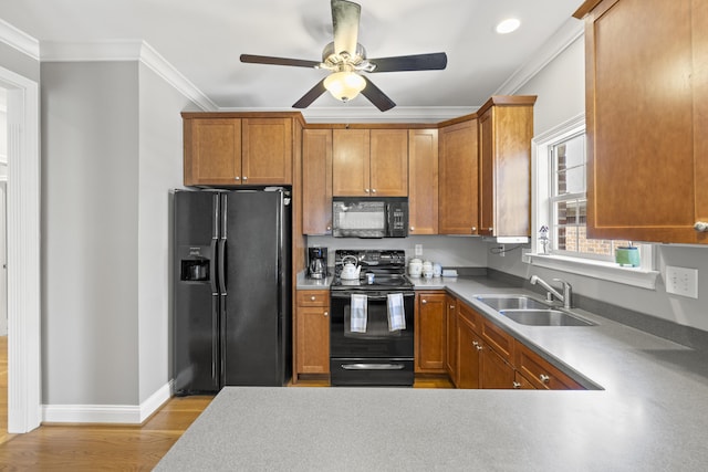 kitchen featuring crown molding, a sink, light wood-style floors, a ceiling fan, and black appliances