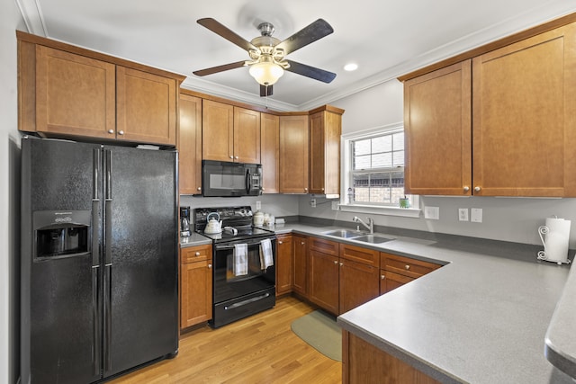 kitchen with light wood-style floors, a sink, brown cabinets, and black appliances