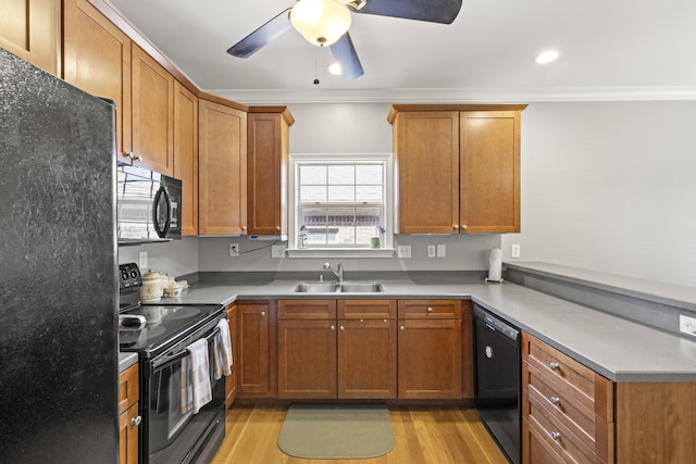 kitchen with a sink, ornamental molding, black appliances, and a peninsula