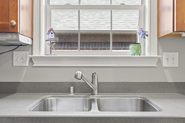 room details featuring brown cabinetry, a sink, and light countertops