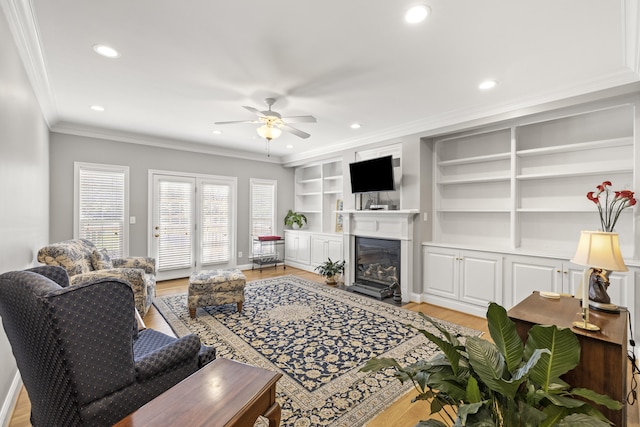 living area with ceiling fan, ornamental molding, recessed lighting, and built in shelves