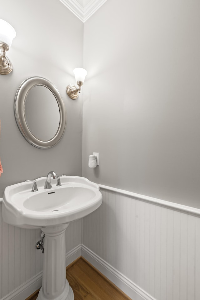 bathroom with wood finished floors, ornamental molding, and a wainscoted wall