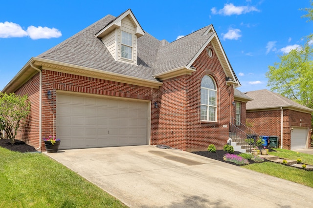 traditional-style house with brick siding, a shingled roof, a garage, and driveway