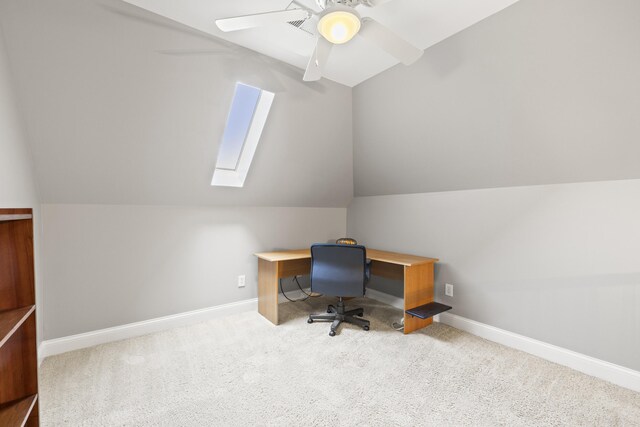 unfurnished office with vaulted ceiling with skylight, baseboards, ceiling fan, and carpet