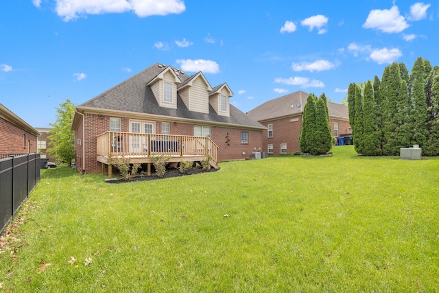 back of house featuring a lawn, a wooden deck, brick siding, fence, and a shingled roof
