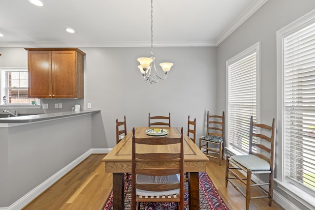 dining area featuring recessed lighting, ornamental molding, light wood finished floors, and a notable chandelier