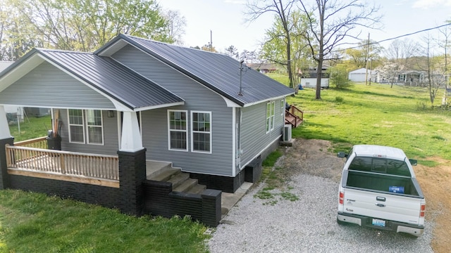 view of property exterior featuring a yard, central AC unit, covered porch, and metal roof