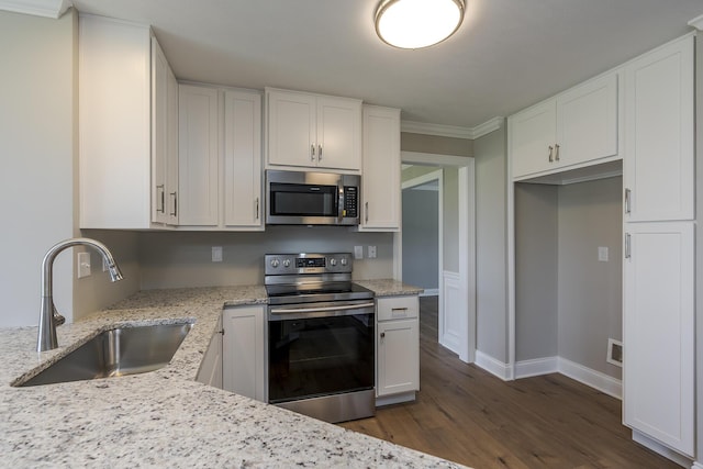 kitchen featuring white cabinetry, appliances with stainless steel finishes, light stone counters, a sink, and dark wood-style floors