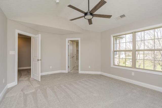 unfurnished bedroom featuring light colored carpet, visible vents, baseboards, and vaulted ceiling