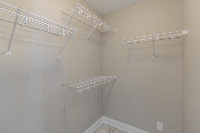 walk in closet featuring marble finish floor