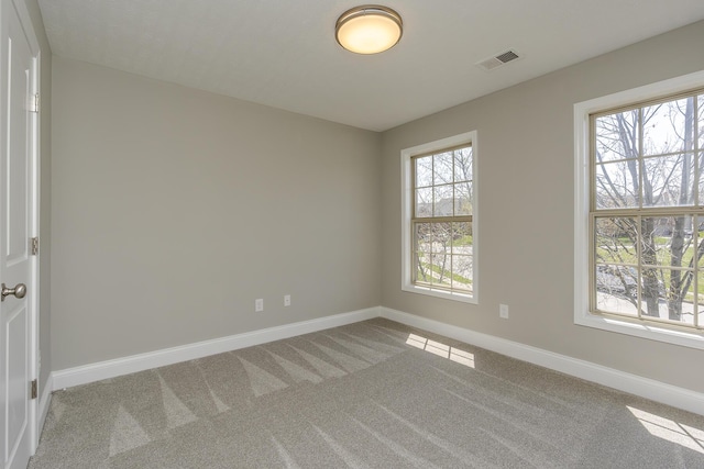 carpeted empty room with visible vents and baseboards