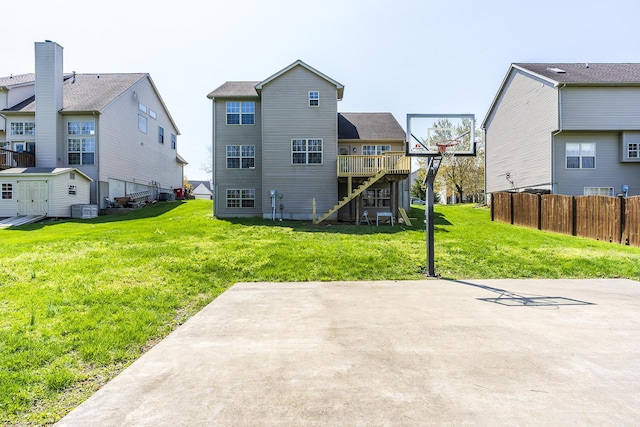 back of property with a yard, a deck, fence, and stairs