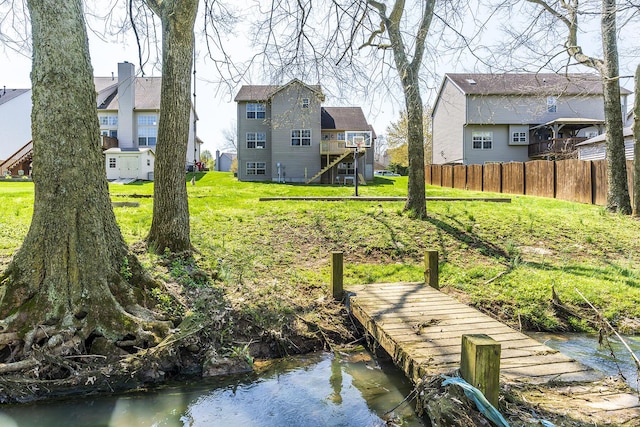 dock area with fence, stairway, and a lawn