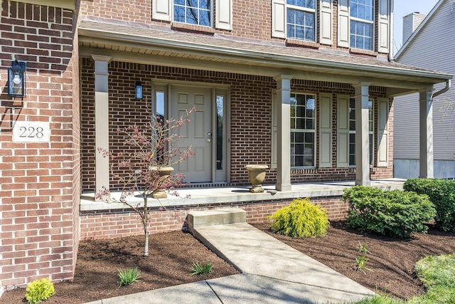 entrance to property featuring brick siding and a porch