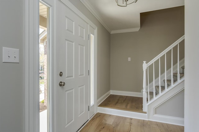 entrance foyer featuring crown molding, wood finished floors, baseboards, and stairs