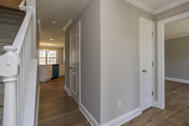 hall featuring baseboards, an inviting chandelier, dark wood-style floors, crown molding, and stairway