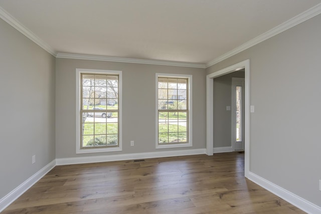 unfurnished room with crown molding, visible vents, baseboards, and wood finished floors