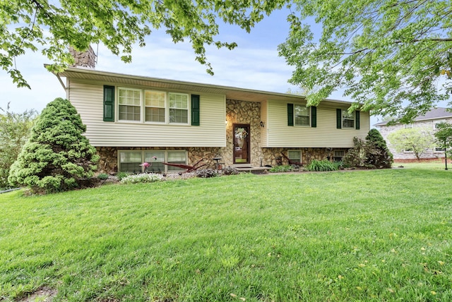 bi-level home with a chimney, stone siding, and a front lawn