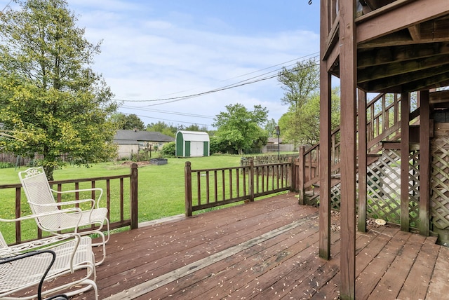 wooden deck featuring a storage shed, stairway, a fenced backyard, an outbuilding, and a lawn