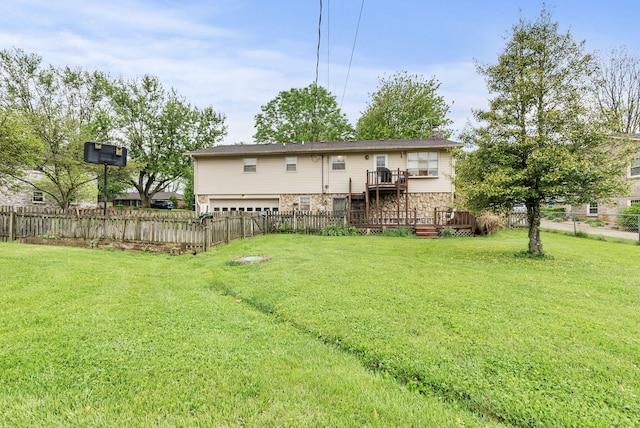 rear view of house featuring an attached garage, a fenced backyard, a lawn, and a wooden deck