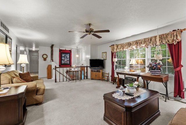 living room with a textured ceiling, ceiling fan, visible vents, and carpet