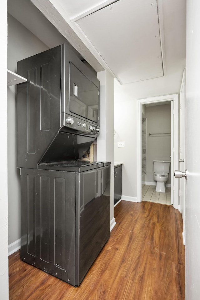 interior space featuring baseboards, stacked washer and dryer, laundry area, and wood finished floors