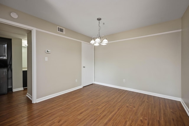 empty room with visible vents, baseboards, a chandelier, and wood finished floors