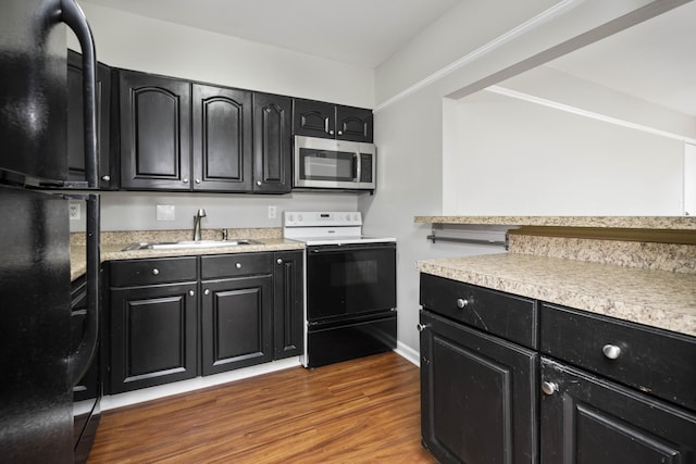 kitchen featuring stainless steel microwave, a sink, electric range oven, and dark cabinetry