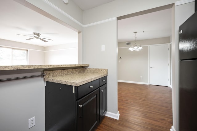 kitchen featuring dark wood-style floors, freestanding refrigerator, visible vents, dark cabinetry, and ceiling fan with notable chandelier