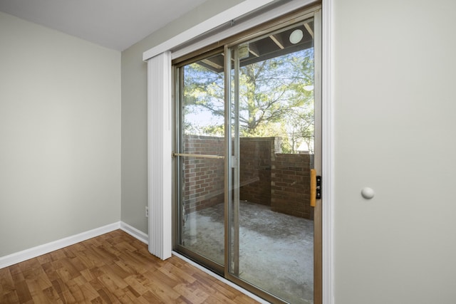 doorway to outside with baseboards and wood finished floors