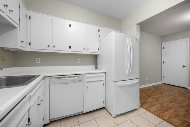 kitchen with white appliances, white cabinets, light tile patterned flooring, a sink, and light countertops
