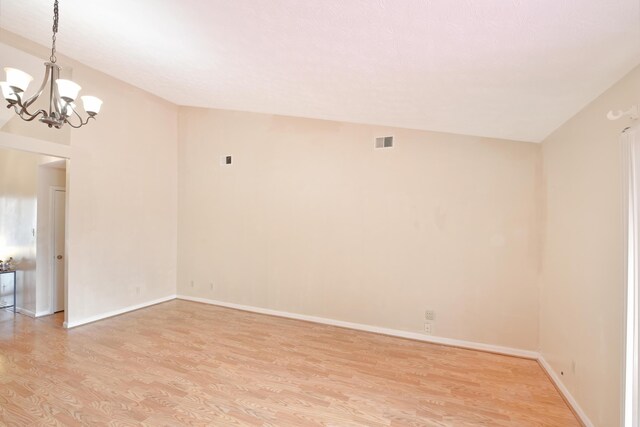 unfurnished room featuring visible vents, baseboards, light wood-type flooring, and a chandelier