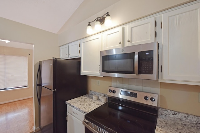 kitchen with white cabinets, tasteful backsplash, vaulted ceiling, and appliances with stainless steel finishes
