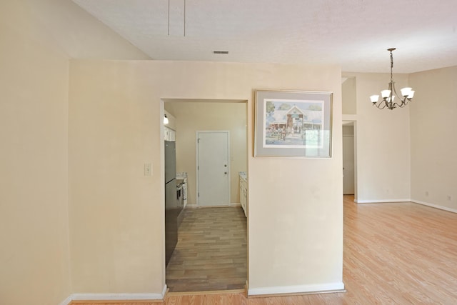 interior space featuring visible vents, baseboards, a chandelier, and light wood-style floors