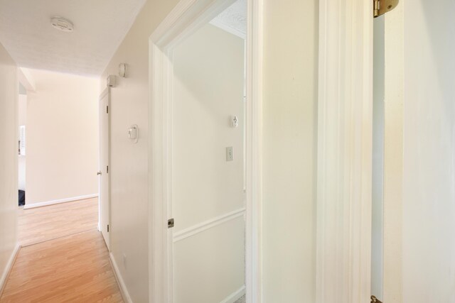 hall with light wood-type flooring and baseboards