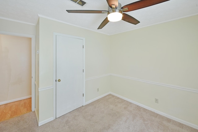 unfurnished bedroom with visible vents, baseboards, ornamental molding, and carpet floors