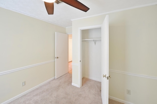 unfurnished bedroom with a closet, visible vents, ceiling fan, crown molding, and carpet flooring