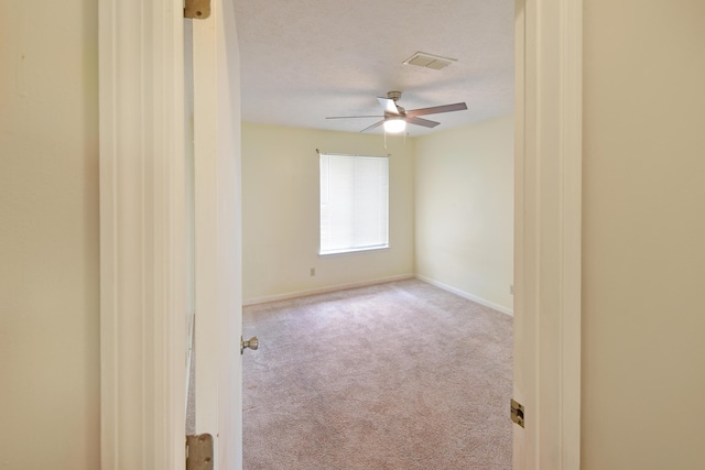 carpeted empty room with visible vents, baseboards, and ceiling fan