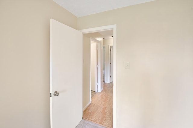 hallway with light wood-type flooring and baseboards