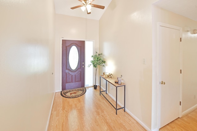 foyer with high vaulted ceiling, a ceiling fan, wood finished floors, and baseboards