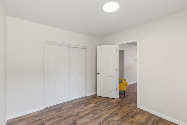 unfurnished bedroom featuring a closet, baseboards, and dark wood-style floors
