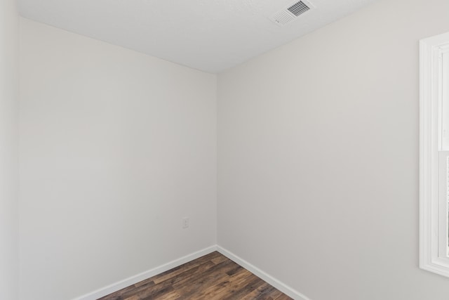 spare room featuring dark wood-type flooring, baseboards, and visible vents
