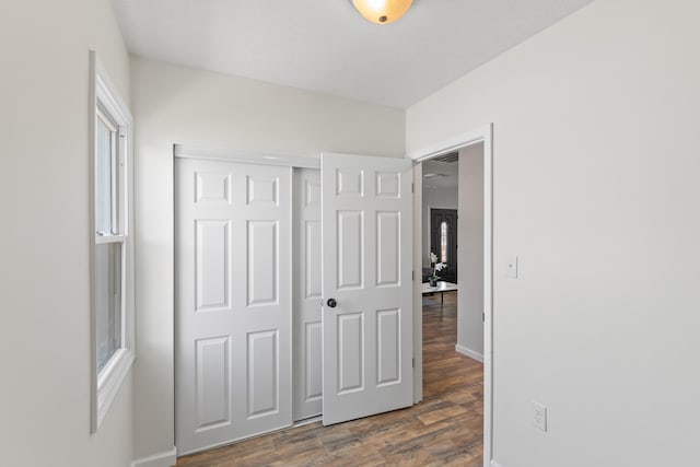 unfurnished bedroom with a closet, dark wood-style floors, and baseboards