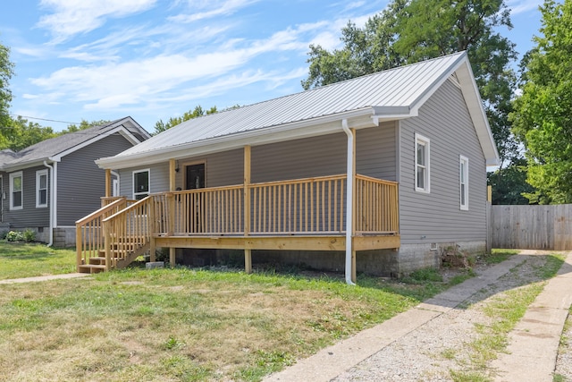 view of front of house featuring metal roof, a front lawn, fence, and covered porch