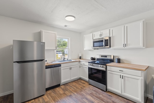 kitchen with stainless steel appliances, visible vents, white cabinetry, and a sink