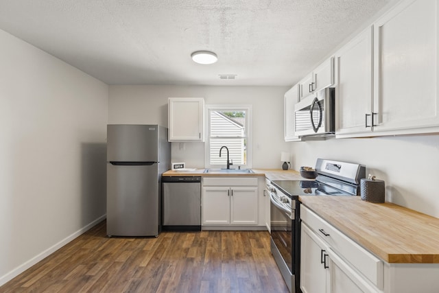 kitchen with white cabinets, a sink, dark wood-style floors, wood counters, and stainless steel appliances
